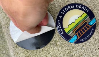 Someone installing an Adopt a Storm Drain mural